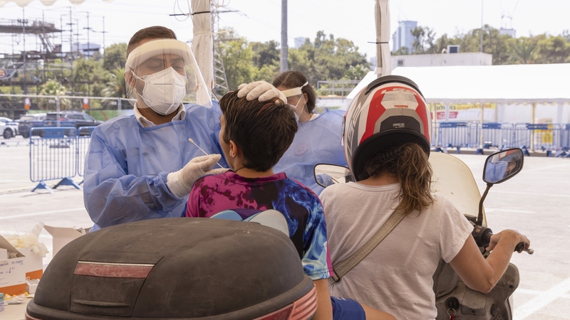 A health worker takes a swab sample from a child at the Magen David Adom drive-thru testing facility in Tel Aviv