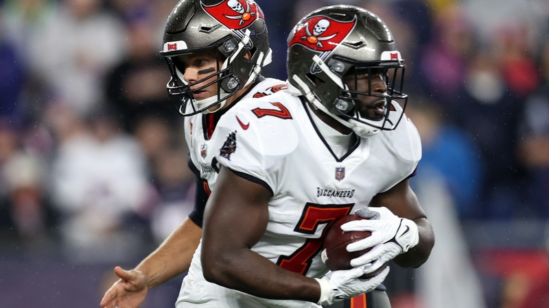 Tom Brady (L) hands the ball off to Leonard Fournette