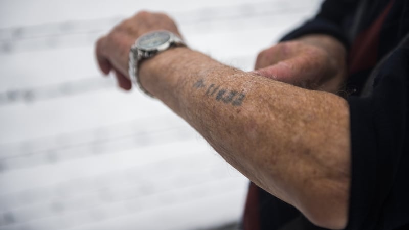 A survivor shows his prisoner number tattooed on his arm as he visits the former Auschwitz concentration camp in Oswiecim