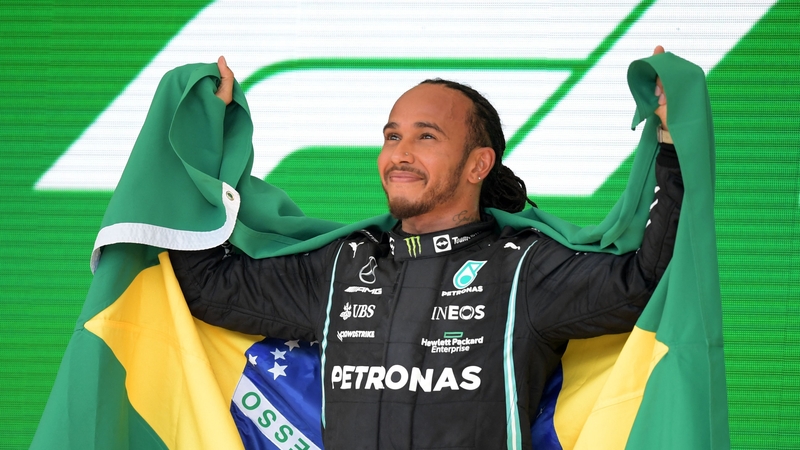 Lewis Hamilton celebrates on the podium with the Brazilian flag