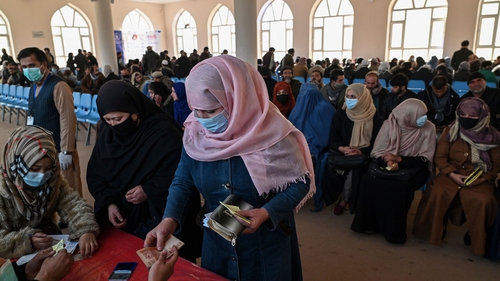A woman collects money during a World Food Programme cash distribution in Kabul