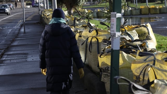A woman walks past sandbags laid out on the seafront in Clontarf, Dublin
