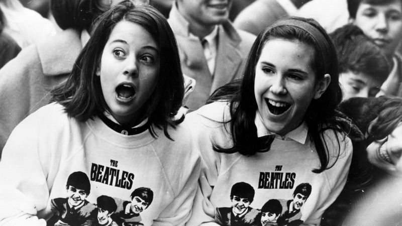 10th February 1964: Two excited girls in Beatles sweatshirts, amongst a crowd of fans in New York