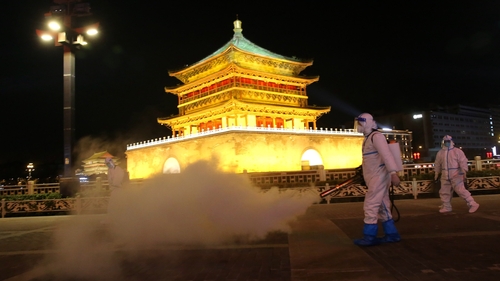 Staff members in protective suits disinfect around Xi'an Bell Tower