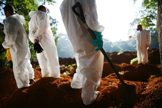 Cemetery workers in protective suits wait before burying the bodies of Covid-19 victims at a cemetery in Sao Paulo, Brazil