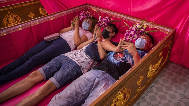 Thai monks cover devotees with a pink sheet during a New Year's Eve resurrection ceremony at Wat Takien in Bangkok, Thailand