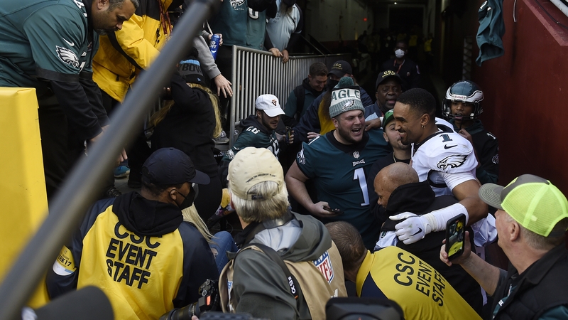 A relieved Jalen Hurts #1 celebrates with fans who fell onto the ground after a railing collapsed.