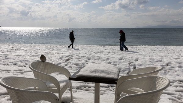 A table and chairs covered in snow on a terrace on the beach in Alimos, a suburb of Athens