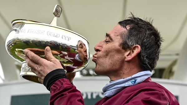 Davy Russell gives the Irish Gold Cup a kiss after prevailing aboard long-shot Conflated