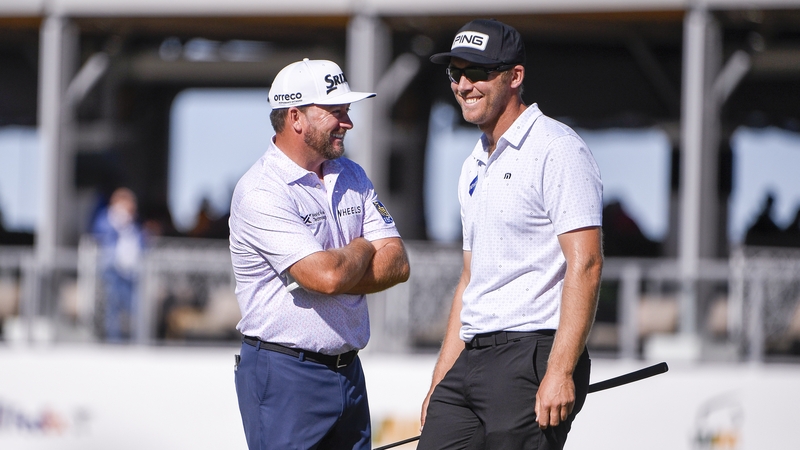Graeme McDowell and Seamus Power of Ireland look toward fans holding an Irish flag at the 17th green during the first round of the WM Phoenix Open