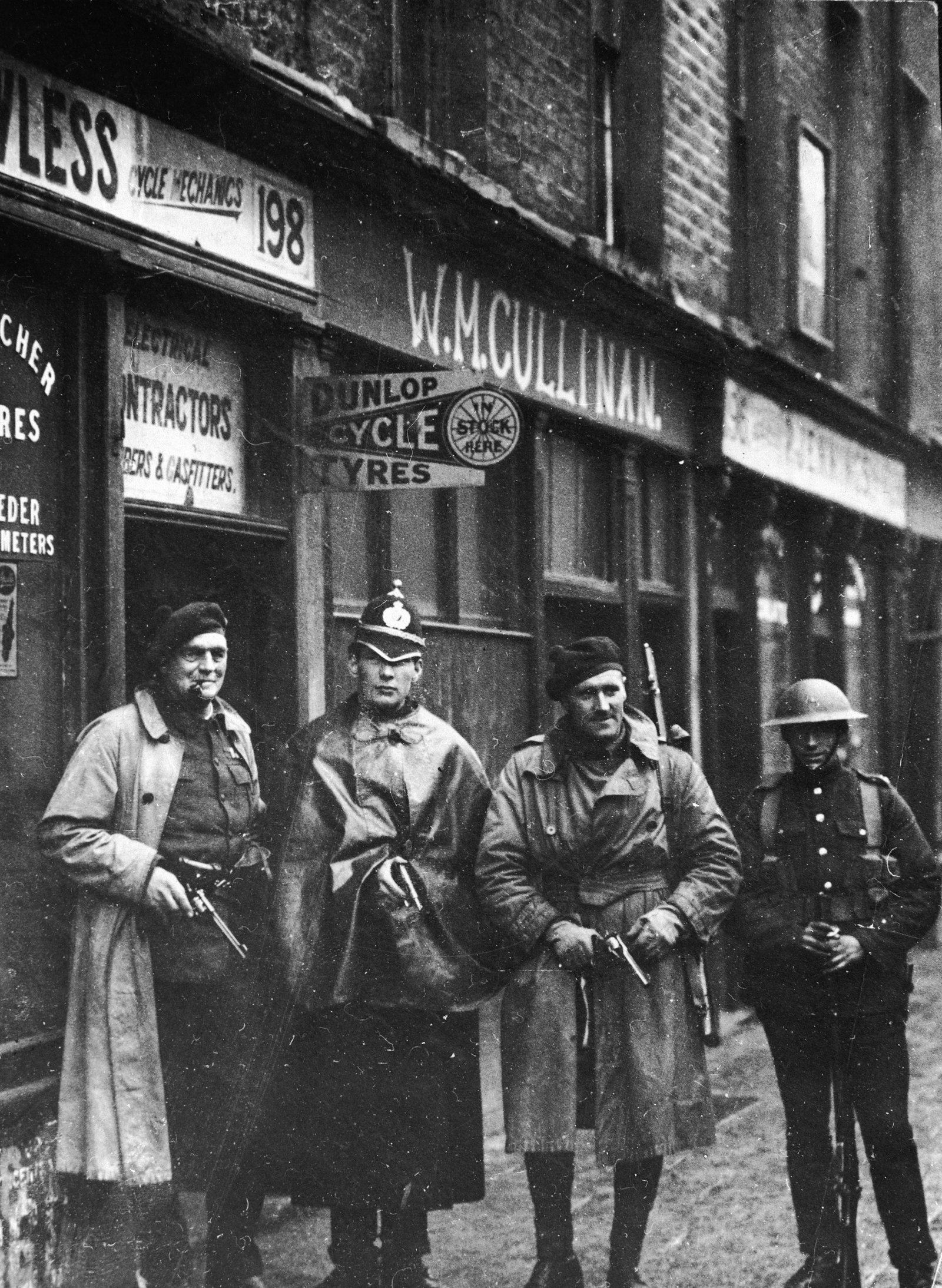 Posed photo of two Auxiliaries, a DMP Constable, and a British soldier in Dublin. The DMP man sheepishly holds a pistol. In fact by October 1920, they had opted out of the war against the IRA. Image: Getty Images