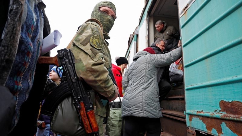 A militant of the self-proclaimed Donetsk People's Republic is seen on a platform, as evacuees board a train before leaving Donetsk