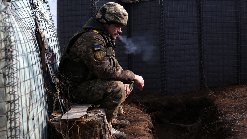 Duine de shaighdiúirí Úcráin ag caitheamh gail ar an teorainn i Luhansk.