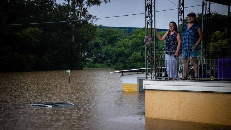 People look at floodwaters from the balcony of their home in West Ipswich, Queensland