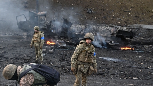 Ukrainian forces look for and collect unexploded shells after fighting in Kyiv