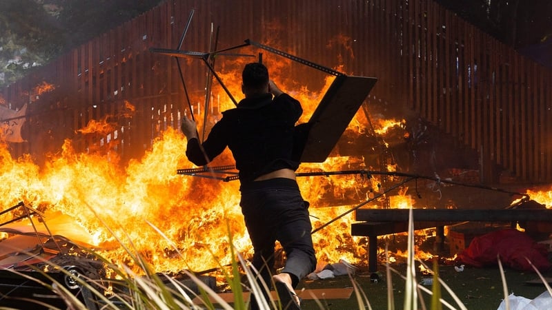 A man throws a desk onto a fire as the protest camp was set alight