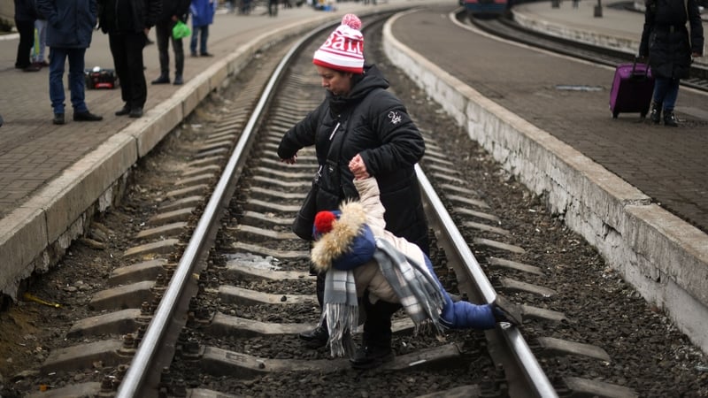 A mother helps a child to cross the train railways at Lviv central train station on 4 March