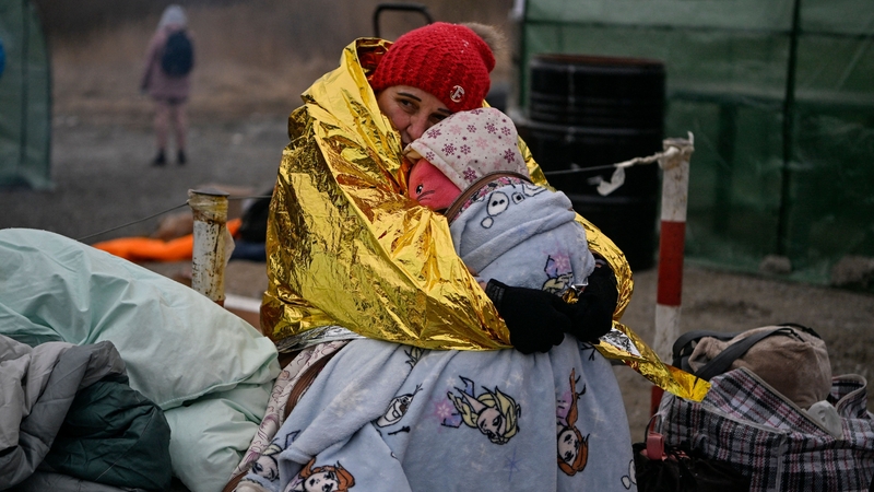 A woman hugs her grandchild as people wait to be transferred to a train station
at the Medyka border crossing in Poland