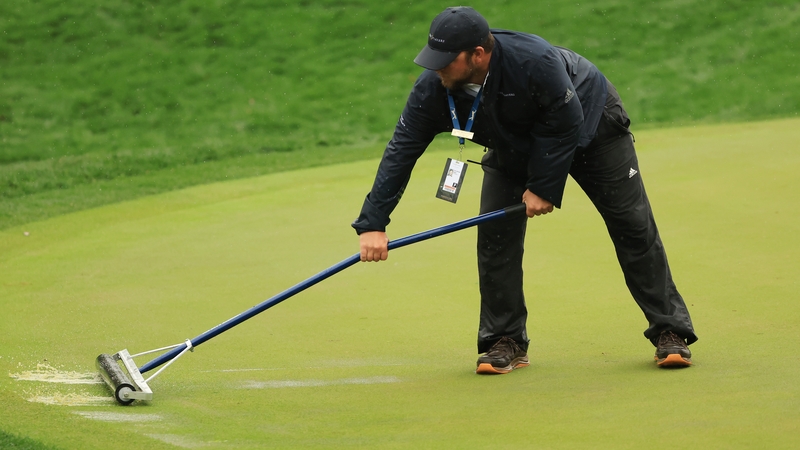 Course assistant superintendent John Michael Clark tries to clear water from a green