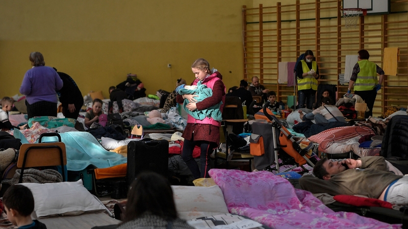 A girl holds her infant sibling in a temporary shelter for Ukraine's refugees in a school in Przemysl, near the Ukrainian-Polish borders on 14 March