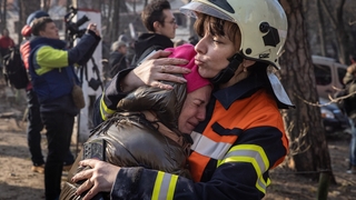 A resident is comforted by an emergency services worker at an apartment building after it was hit by a Russian attack in the early hours of the morning on March 15, 2022 in Kyiv