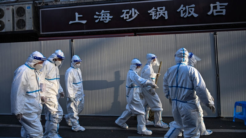 Workers wearing protective clothes in an area where barriers are being placed to close off streets around some lockdown areas after the detection of new cases of covid-19 in Shanghai