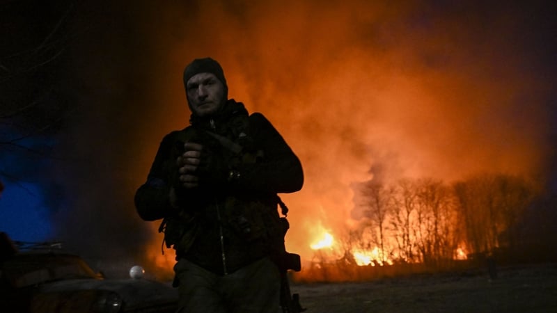A Ukrainian serviceman looks on as he stands in front of a burning warehouse after a shelling in Kyiv on 17 March