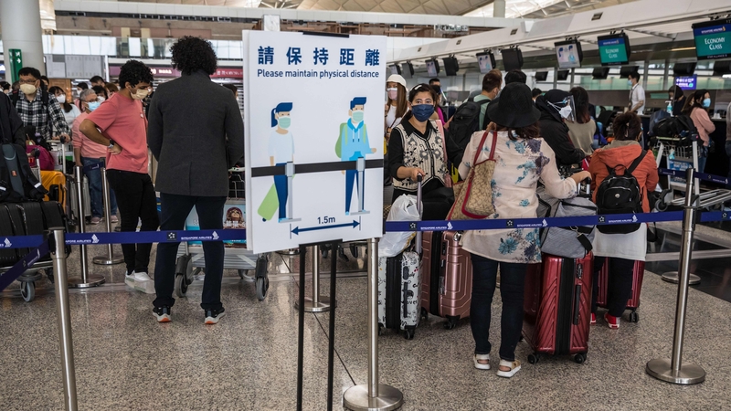 People wait in a queue to check-in for their flight at Hong Kong International Airport in Hong Kong