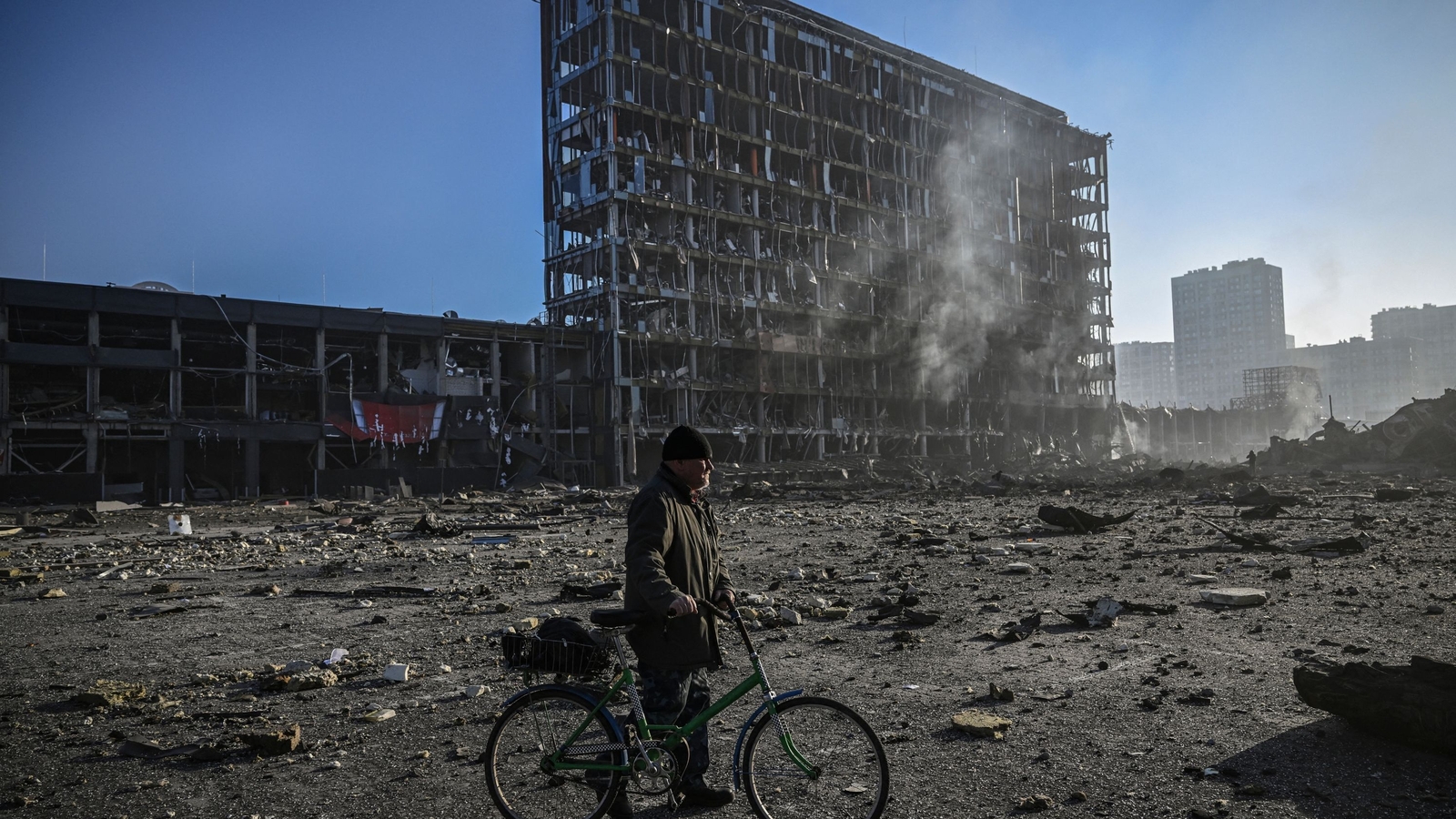 A man with his bicycle walks through debris outside a destroyed shopping centre in Kyiv