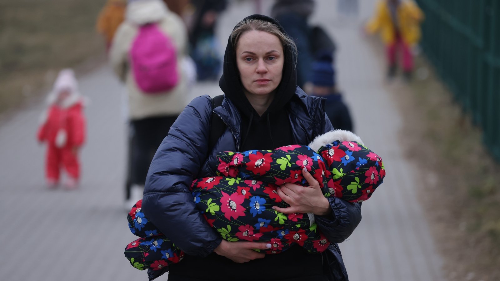 A mother carrying an infant arrives in Poland at the Medyka border