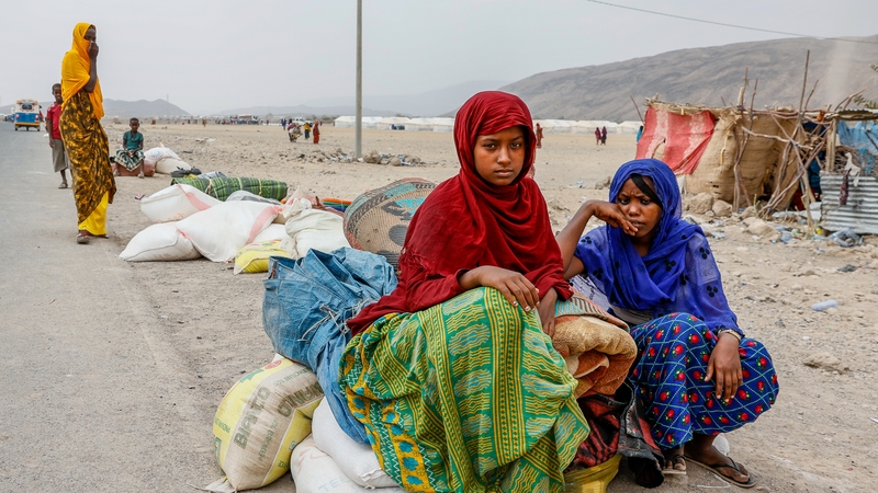 Two women sit on bags of aid dispensed at the Silsa Internally Displaced Peoples' camp in Silsa, Ethiopia