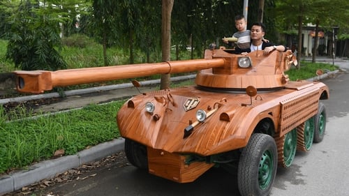 Truong Van Dao and his son ride in a wooden tank made from the conversion of an old minibus