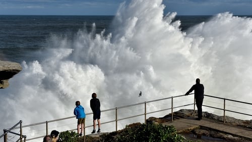 Residents watch a wave crashing into rocks at Bondi Beach in Sydney today