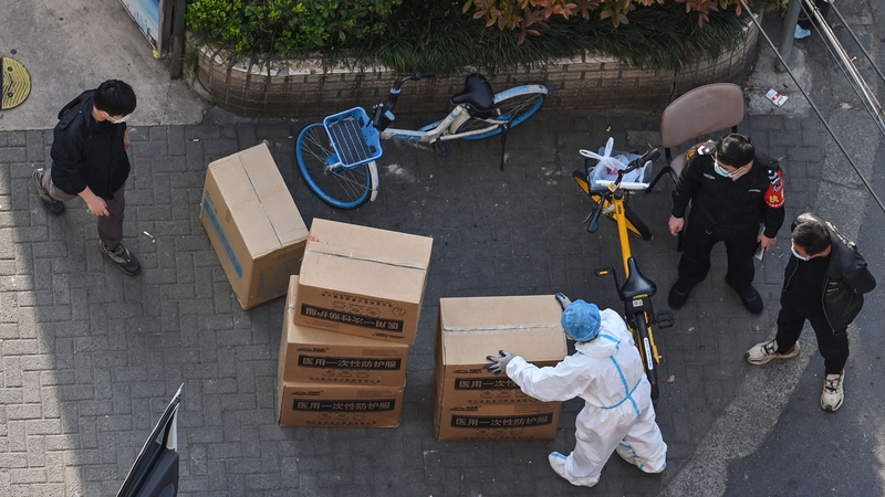A worker wearing personal protective gear offloading boxes in Shanghai today