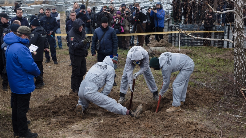 Forensics experts exhume the bodies of a mother and two children buried in Bucha, Ukraine
