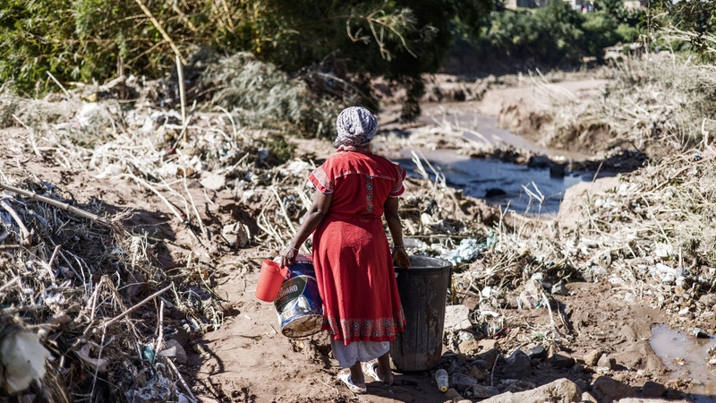 A woman in the Inanda district of Durban near a waterfall created by a collapsed road, after flooding that killed nearly 400 people