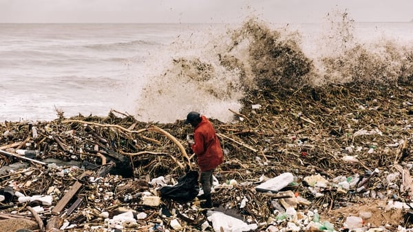 A man collects plastic bottles amongst debris at the Blue Lagoon beach in Durban