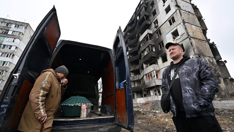A father cries in front of a minivan with the coffin of his son, who died in this apartment block in Borodianka after a Russian missile strike