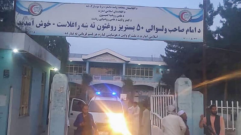 Taliban fighters and medical staff stand outside the gate of an hospital as they prepare to attend to the casualties after an explosion at Imam Sahib district in Kunduz province
