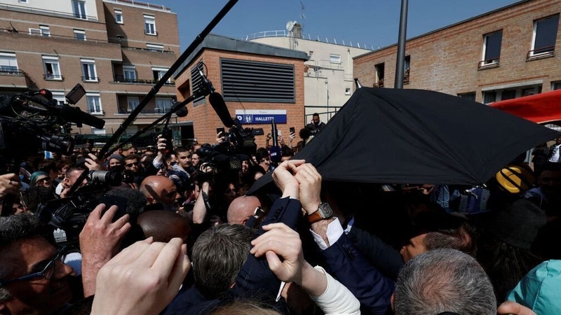 Emmanuel Macron shielded from the tomatoes with an umbrella