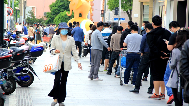 Residents queue up to enter a supermarket in Shanghai