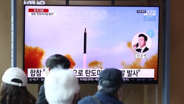 Civilians watch file footage of a North Korean nuclear missile test