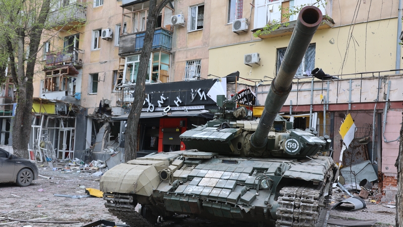 A tank is seen in front of the damaged building as Russian attacks continue in Mariupol