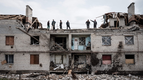Workers clean rubble from a building destroyed by shelling in Cherkaske, eastern Ukraine