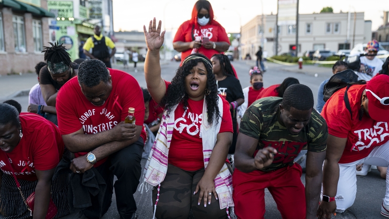 People pray at the scene of a mass shooting at a Tops Friendly Market in Buffalo, New York state