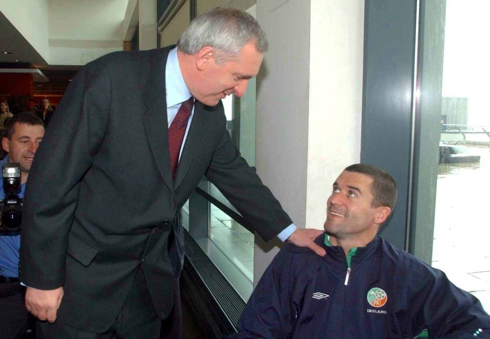 Roy Keane meets Taoiseach Bertie Ahern at Dublin Airport, where there were no seats for the players as they waited to board plane
