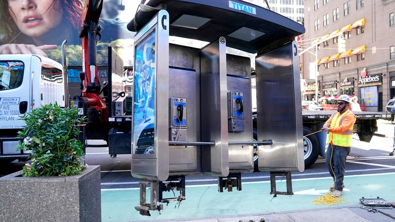 Workers remove the payphone near Seventh Avenue and 50th Street in Midtown Manhattan, New York City
