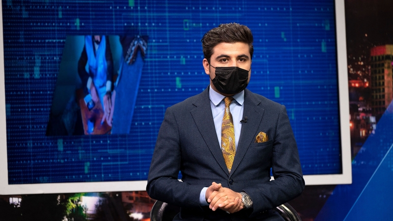 Nisar Nabil, presenter for TOLOnews, wearing a black mask speaks during a live broadcast
