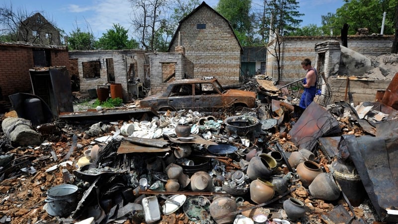 A man cleans up debris of his house destroyed by shelling in the village of Moshchun, Kyiv