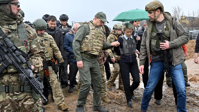 Ukrainian Prime Minister Denys Shmyhal (C-L) helps European Commission President Ursula von der Leyen during a visit to a mass grave in the town of Bucha on 8 April
